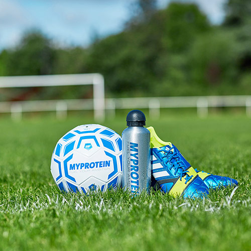 Myprotein futbolo, vandens butelių ir futbolo batai ant žolės futbolo aikštė