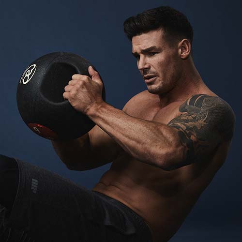 Atleta a fazer exercício no ginásio com uma bola pesada